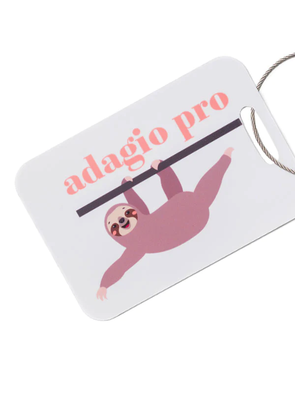 
                      
                        This image shows a white rectangular luggage tag with rounded corners. On the tag, there is an illustration of a cute, smiling sloth hanging from a black bar. The sloth is drawn in a simplistic, cartoonish style, with a light brown body and darker brown patches around its eyes. Above the sloth, in large, playful pink letters, is the text "adagio pro." The tag has a small hole in one corner through which a silver wire loop is threaded, presumably for attaching the tag to a piece of luggage.
                      
                    