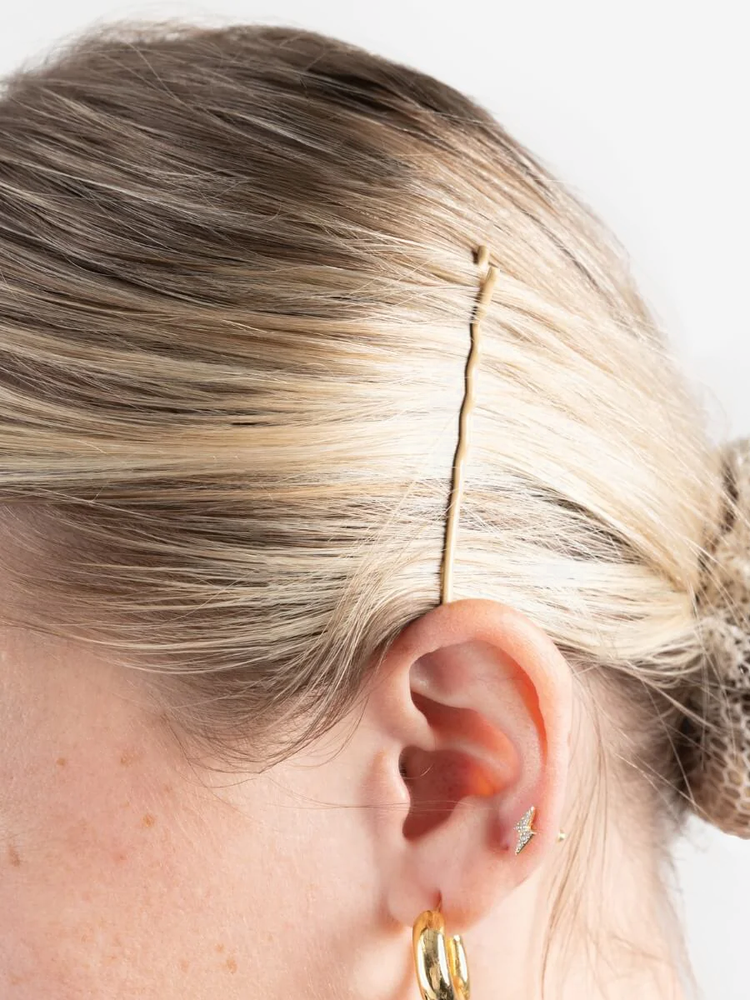 
                      
                        A super close-up of the side of a person's head, blonde hair pulled back into a bun, and a single blonde bobby pin above the ear. She accessorizes with a gold hoop earring.
                      
                    