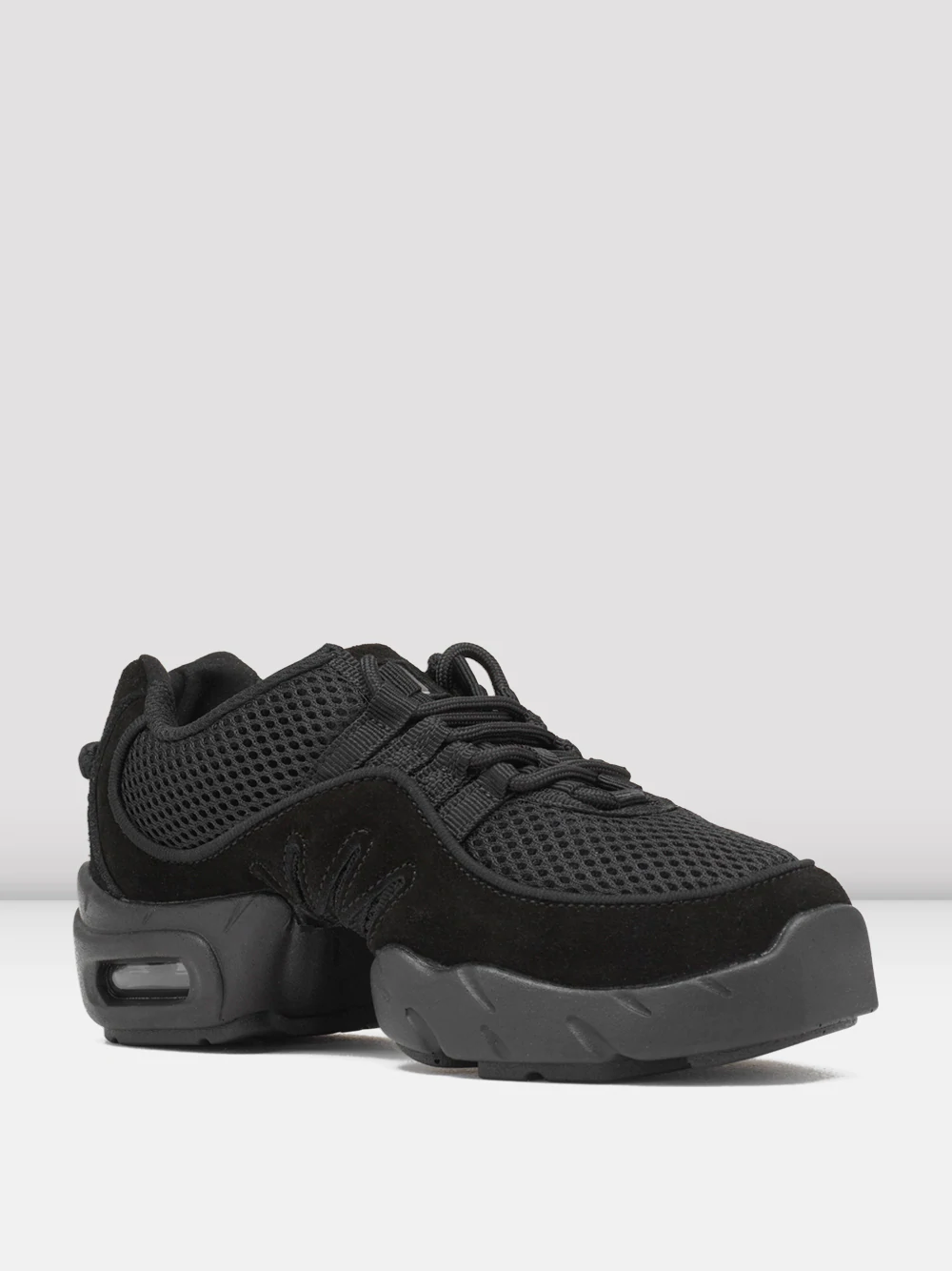 A pair of black sneakers with mesh and suede textures. The shoes feature a thick, cushioned sole with visible air pockets in the heel for added comfort. Matching black laces are tied on top, and the background is a plain, light grey.