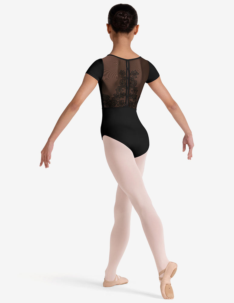 
                      
                        Young dancer wearing a black leotard with sheer back panel on a white background
                      
                    