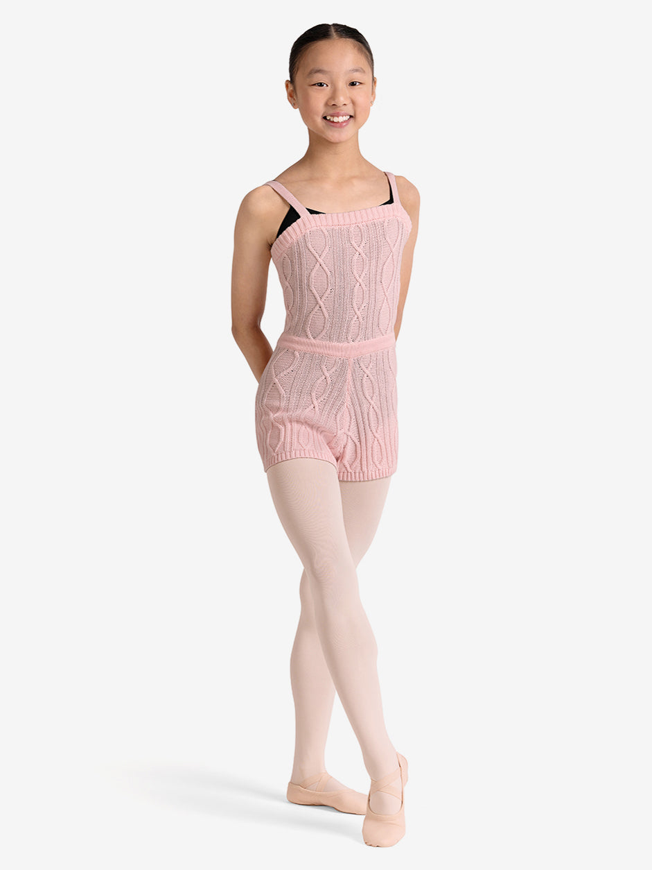 Young girl wearing a pink cable knit unitard on a white background
