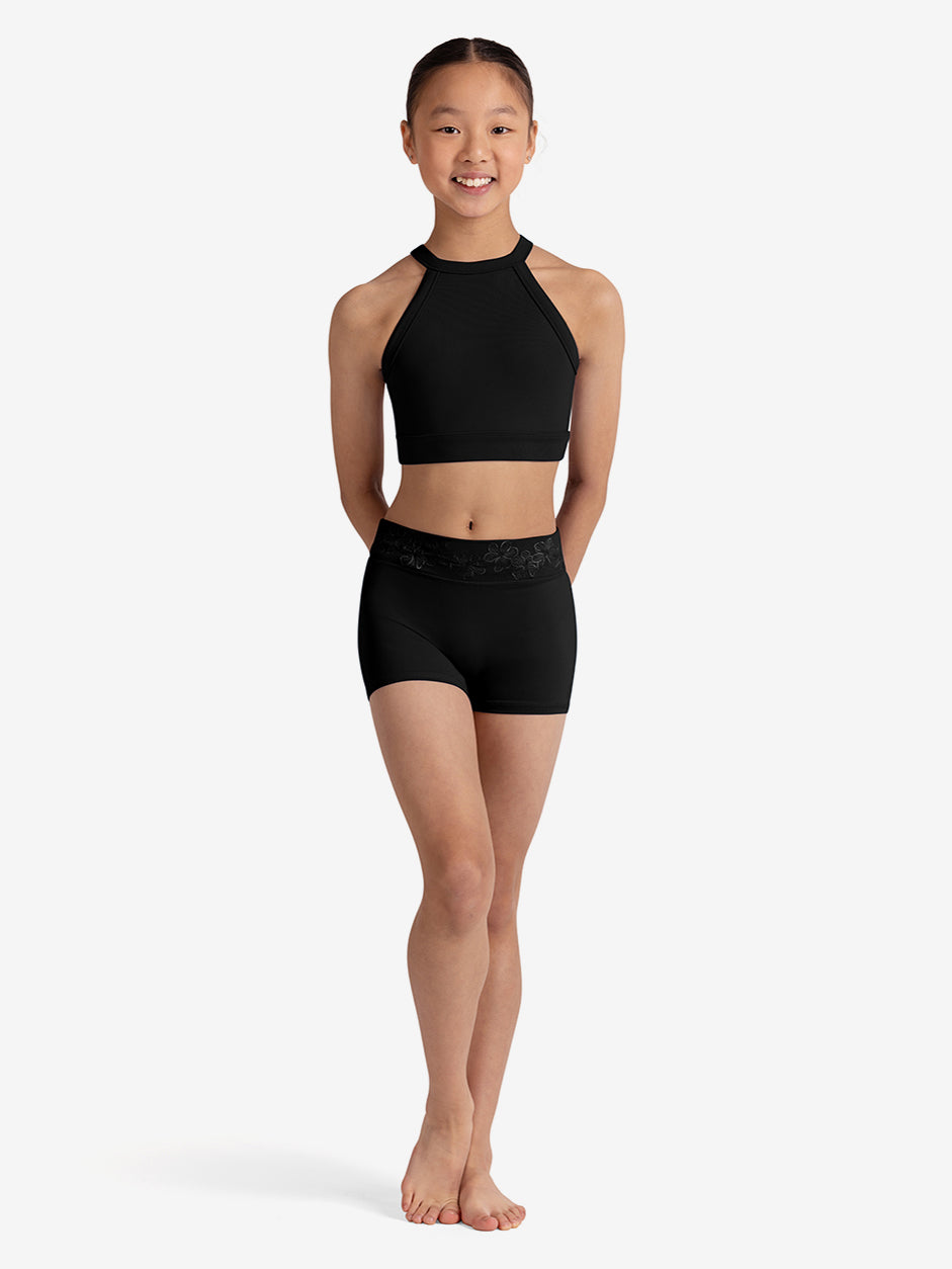 Young girl wearing a black sports bra and shorts on a white background