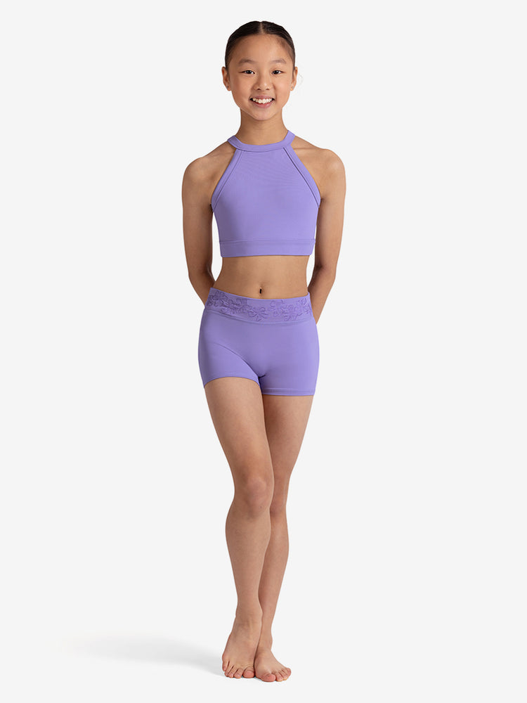 
                      
                        Young girl wearing a lilac sports bra and shorts on a white background
                      
                    