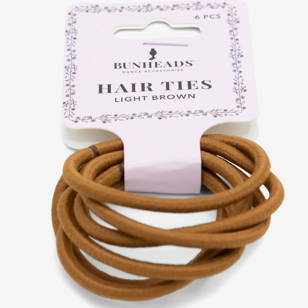 
                      
                        A single package of six light brown hair ties against a plain background.
                      
                    