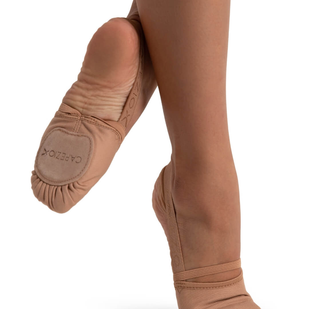 
                      
                        Close-up of a person's legs wearing light suntan colored pirouette shoes, back foot lifted in the air and right foot on releve
                      
                    