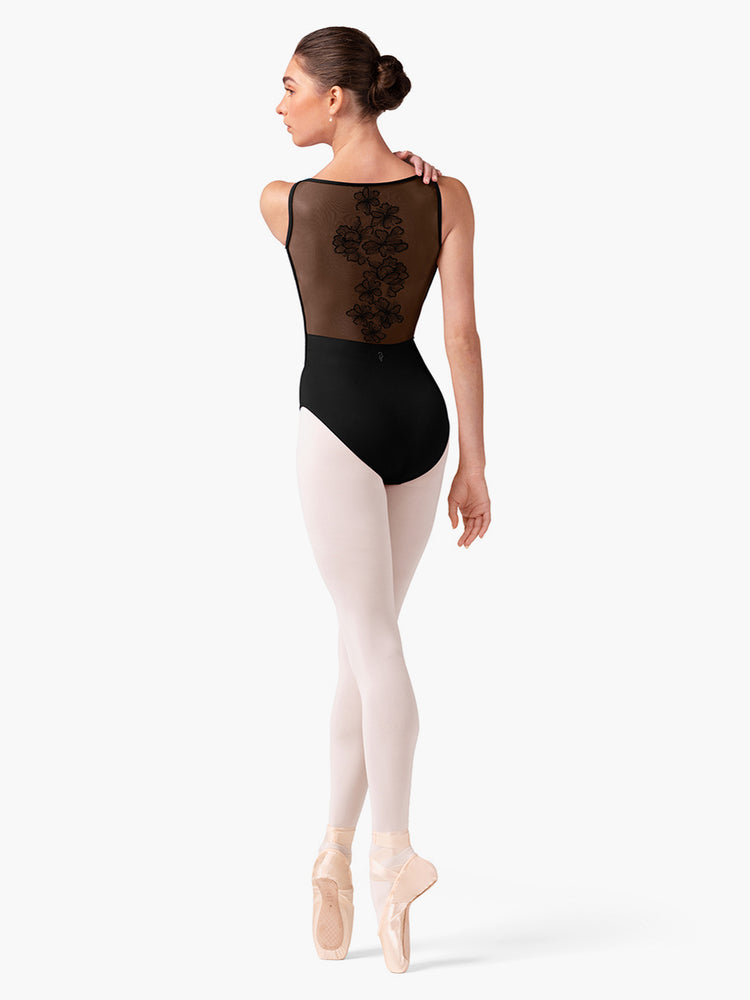 
                      
                        Dancer wearing a black leotard with sheer overlay and pink tights on a white background
                      
                    