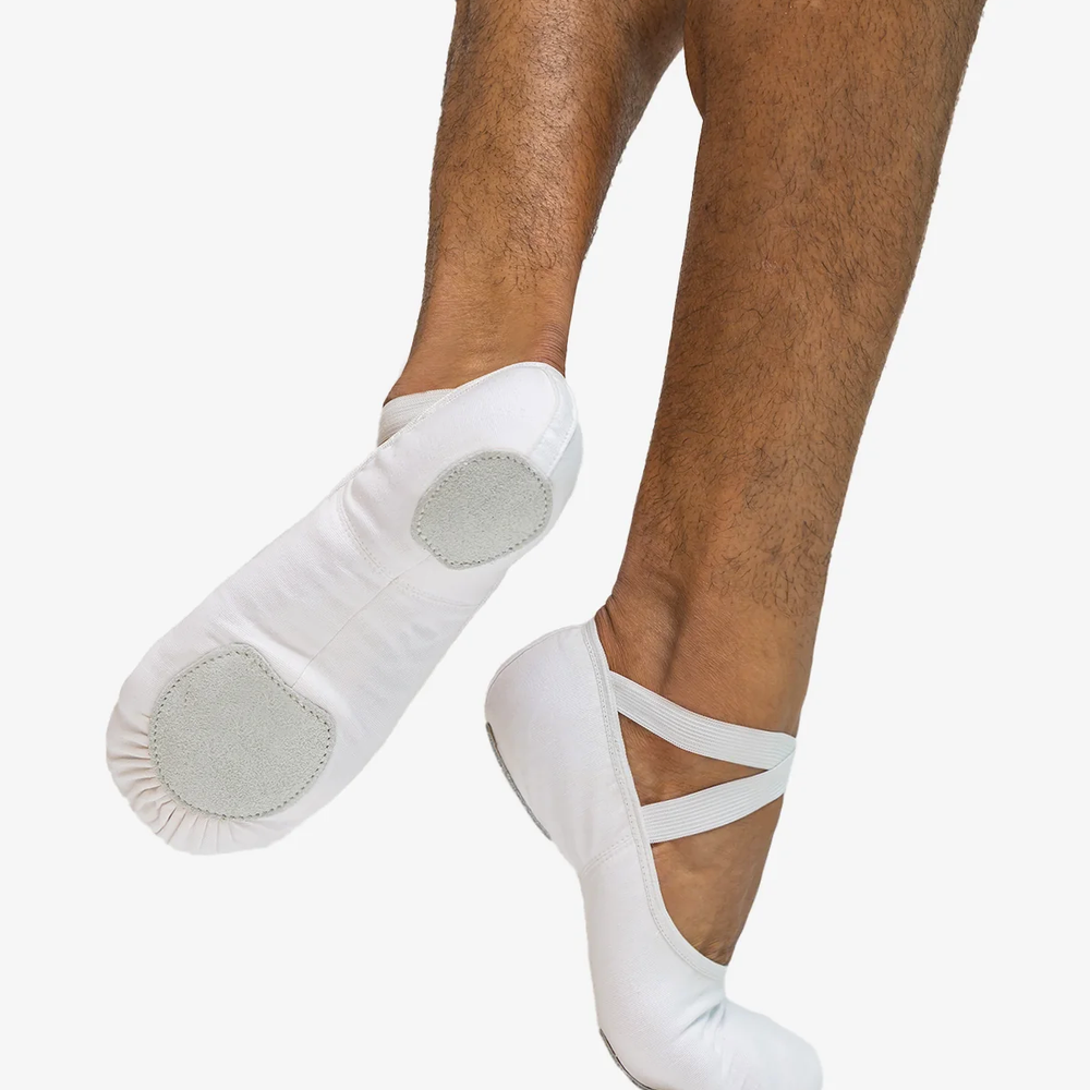 Close-up of a man's legs right foot on releve, back foot lifted showing the bottom of the white ballet shoe