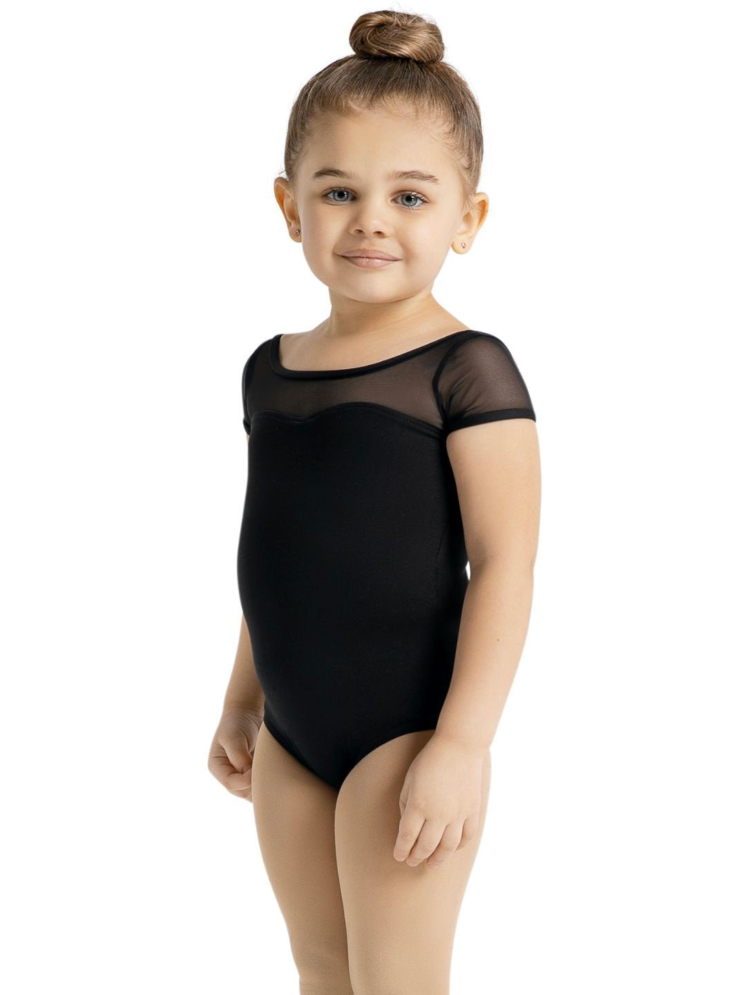 A small child with a top knot bun stands sweetly in a black short sleeve leotard.