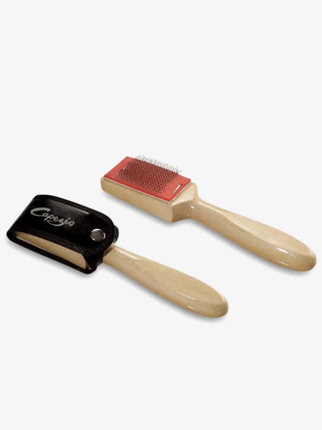 A pair of wire brushes lay side-by-side. The handles are a natural wood look, the brush is wire, one has a black cap closed over the wire brush with a snap and features a Capezio logo. Light grey background.