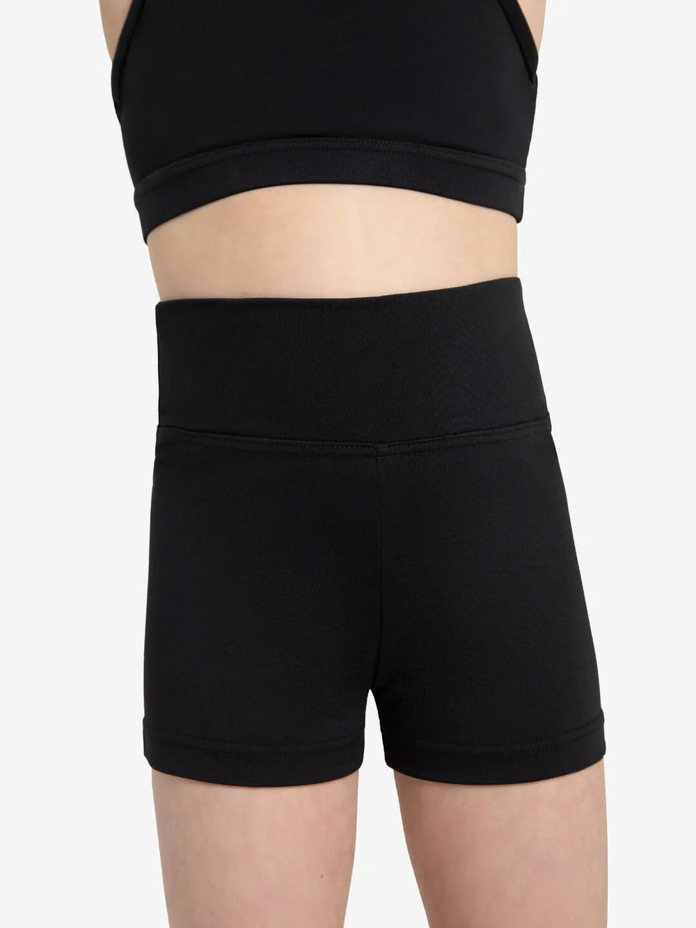 A close-up of a child's torso wearing a black crop top and high waisted, black shorts