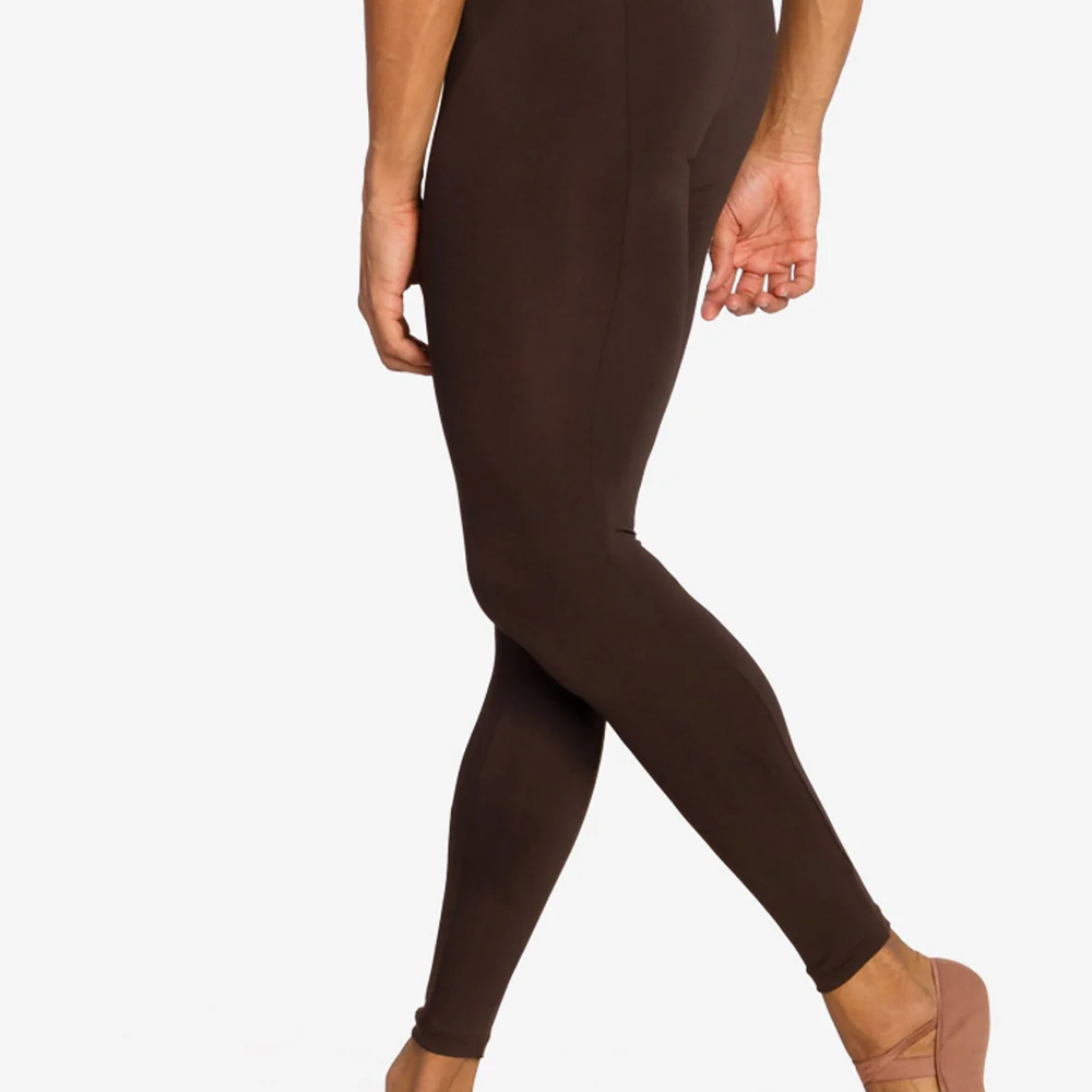 A close-up of the back of a male dancer wearing coffee colored tight leggings. His back leg is extended slightly behind and supported on the toes. 