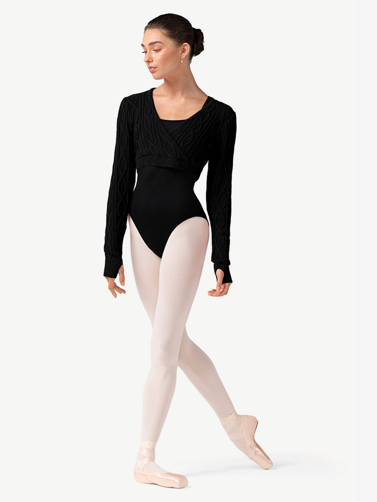 Ballerina in a black sweater over a leotard and pink tights on a white background