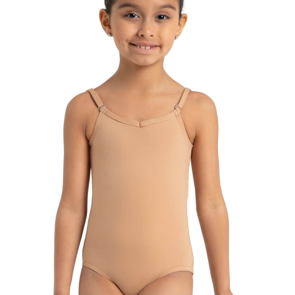 A girl faces forward, hands stretched outward at the side of her hips, her dark hair is pulled back, she has a slight smile and wears a light suntan, adjustable strap leotard.