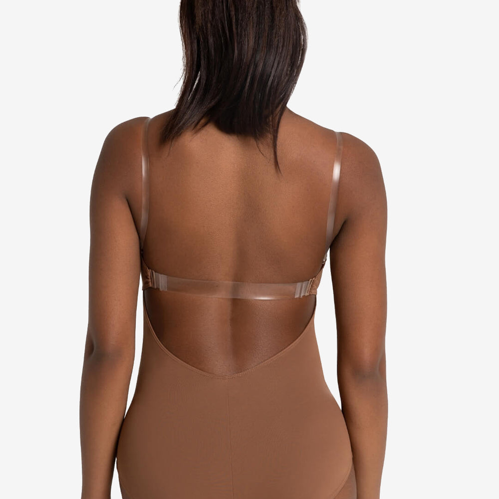 
                      
                        The back of a dancer with long, dark hair pulled into a high ponytail. She is wearing a mocha colored skintone leotard with a low back and clear back strap and clear shoulder straps.
                      
                    