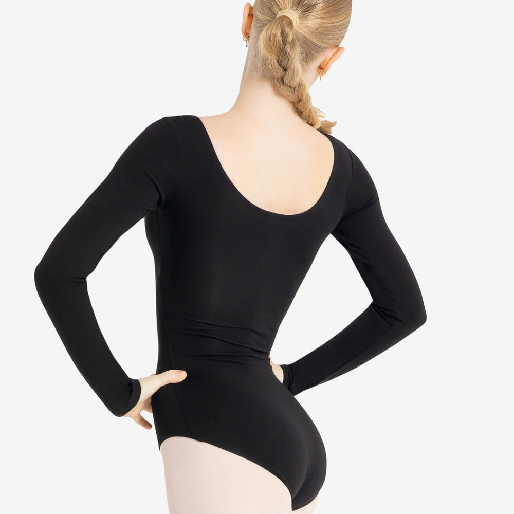 A person with long blond hair tied in a single braid is shown from the back. They are wearing a black long-sleeve leotard and light-colored tights. The person stands with hands on hips against a plain white background.