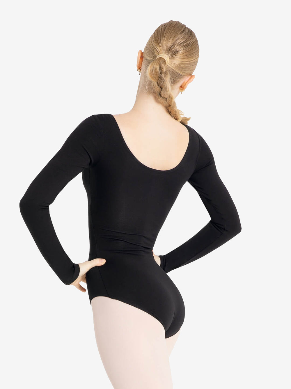 A person with long blond hair tied in a single braid is shown from the back. They are wearing a black long-sleeve leotard and light-colored tights. The person stands with hands on hips against a plain white background.