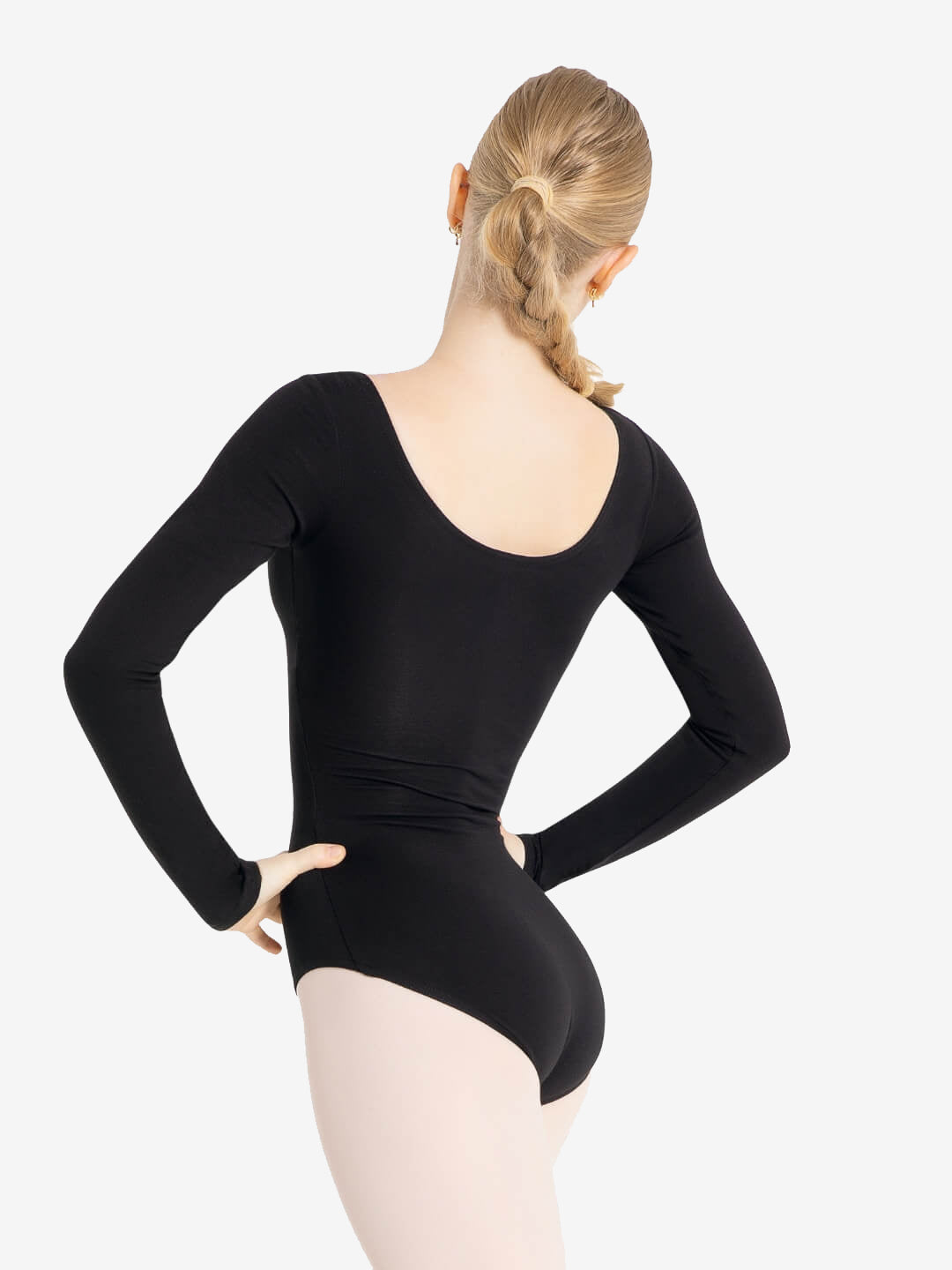 A person with long blond hair tied in a single braid is shown from the back. They are wearing a black long-sleeve leotard and light-colored tights. The person stands with hands on hips against a plain white background.