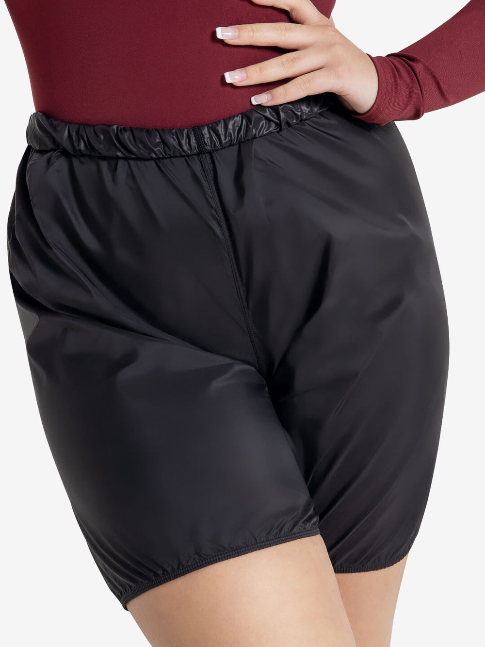 A close-up of a person wearing thigh length rip-stop shorts, the top is folded over, part of a burgundy top is seen and a manicured hand rests on one hip.