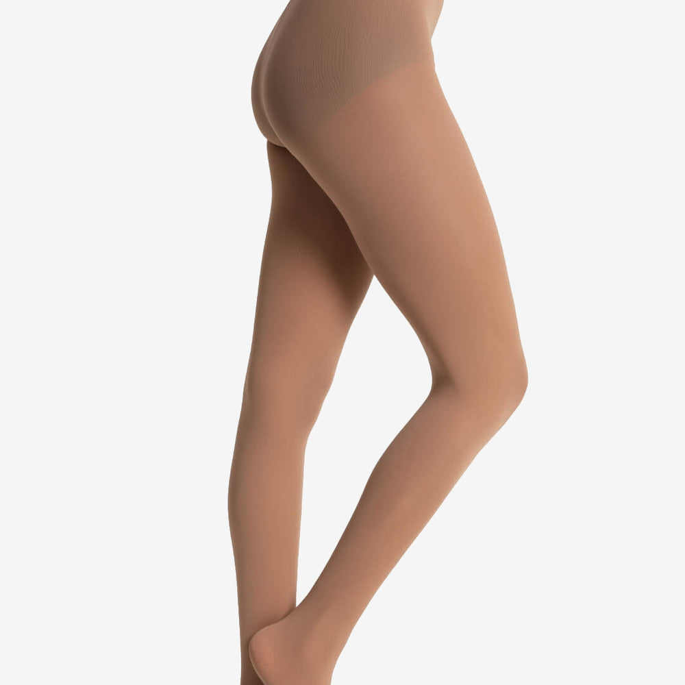
                      
                        A woman is seen from the waist down wearing light suntan tights over a black leotard, her front foot perched on its toes, against a solid light grey background.
                      
                    