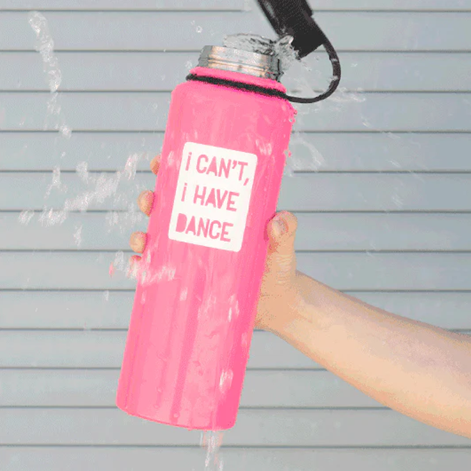 Pink water bottle with 'I Can't, I Have Dance' text held by a person against a gray background.