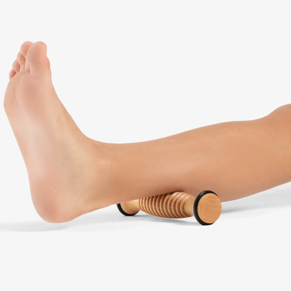
                      
                        A close-up of a foot rolling out ankle muscles on a wood footsie roller
                      
                    