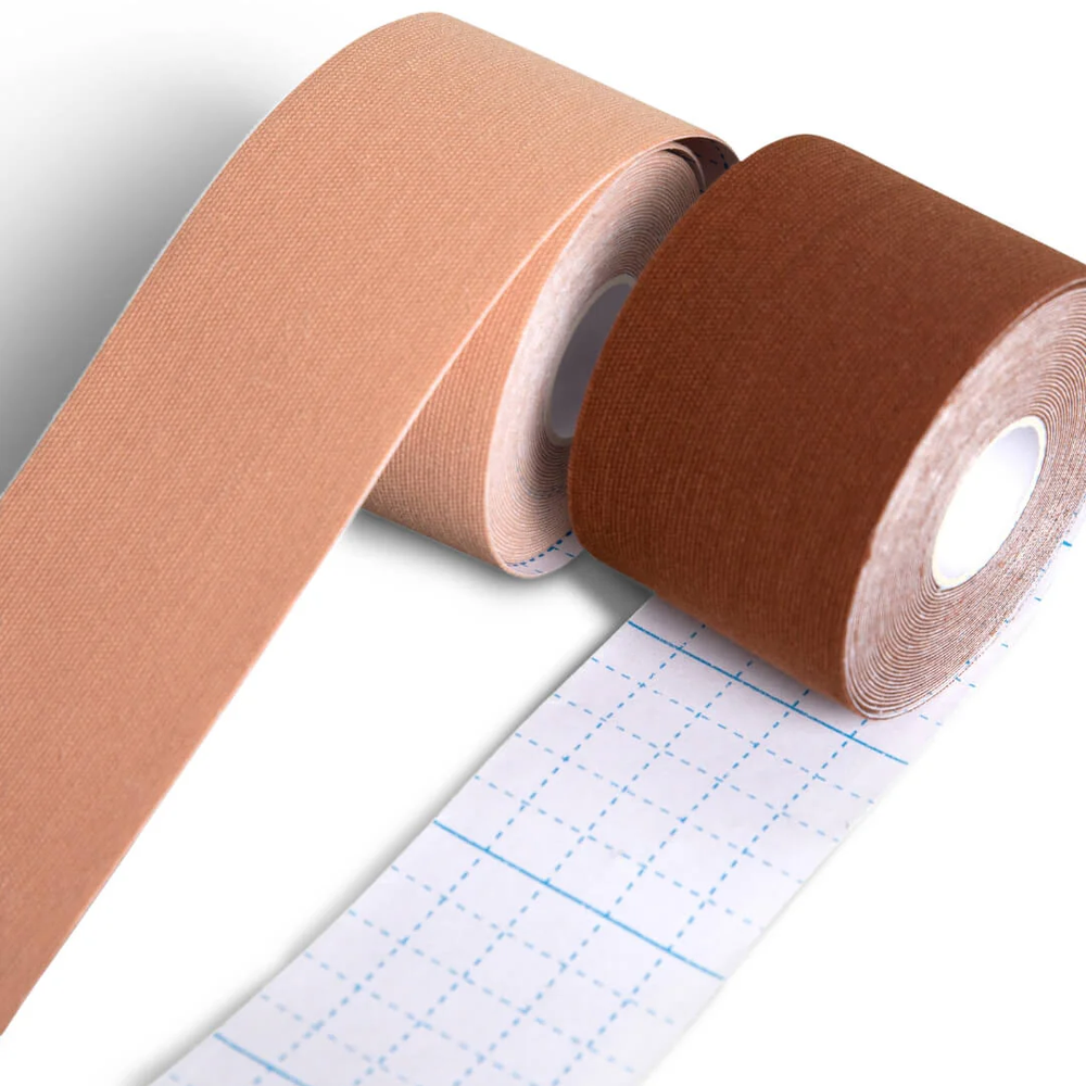 Two rolls of kinesiology tape side-by-side, a lighter nude is rolling over the top, a darker nude is rolling under the roll showing off the dividing lines for cutting.