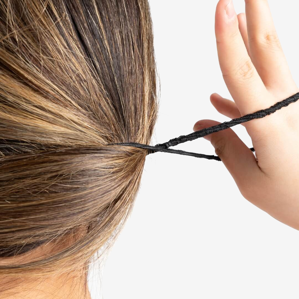 
                      
                        A close-up of a female pulling her black hair tie to the right, with her hand, and twisting it in motion of creating a ponytail.
                      
                    