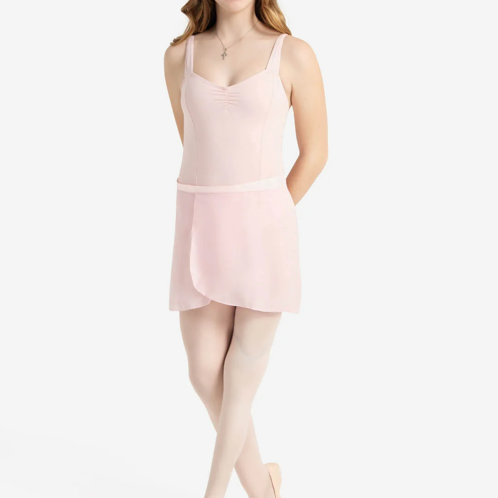 
                      
                        Young woman wearing a light pink leotard and skirt set on a plain background
                      
                    