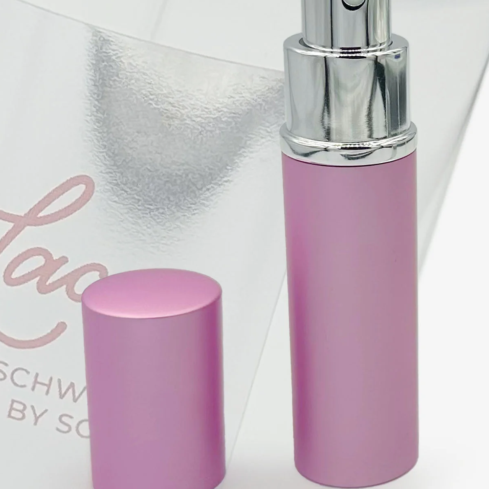A close-up of a pink perfume bottle, top off to show spray nozzle.
