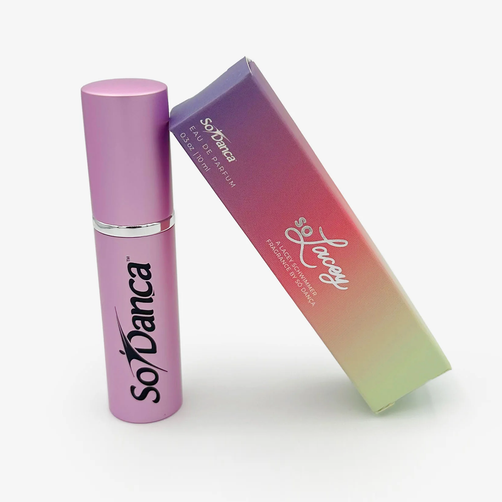 A colorful soLacey branded box leans against a small fuschia perfume bottle with the black So Danca logo on the front 
