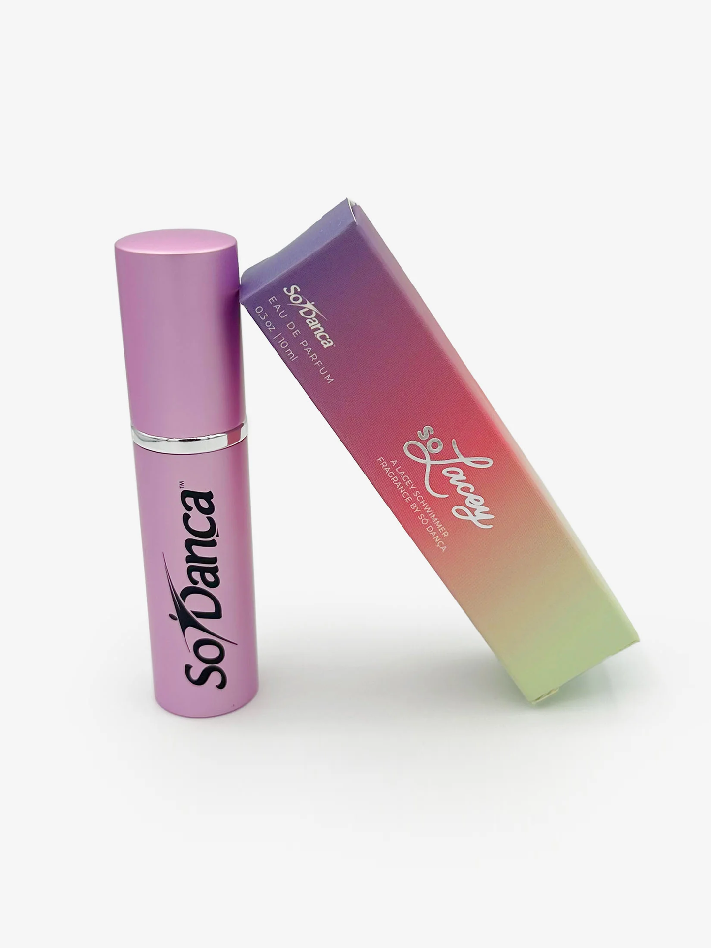 A colorful soLacey branded box leans against a small fuschia perfume bottle with the black So Danca logo on the front 