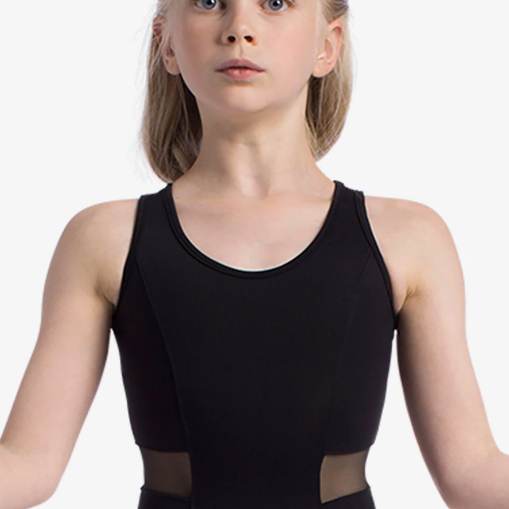 A young blonde girl with her hands held outwards at her sides is wearing a black tank leotard with mesh inserts at the waist.