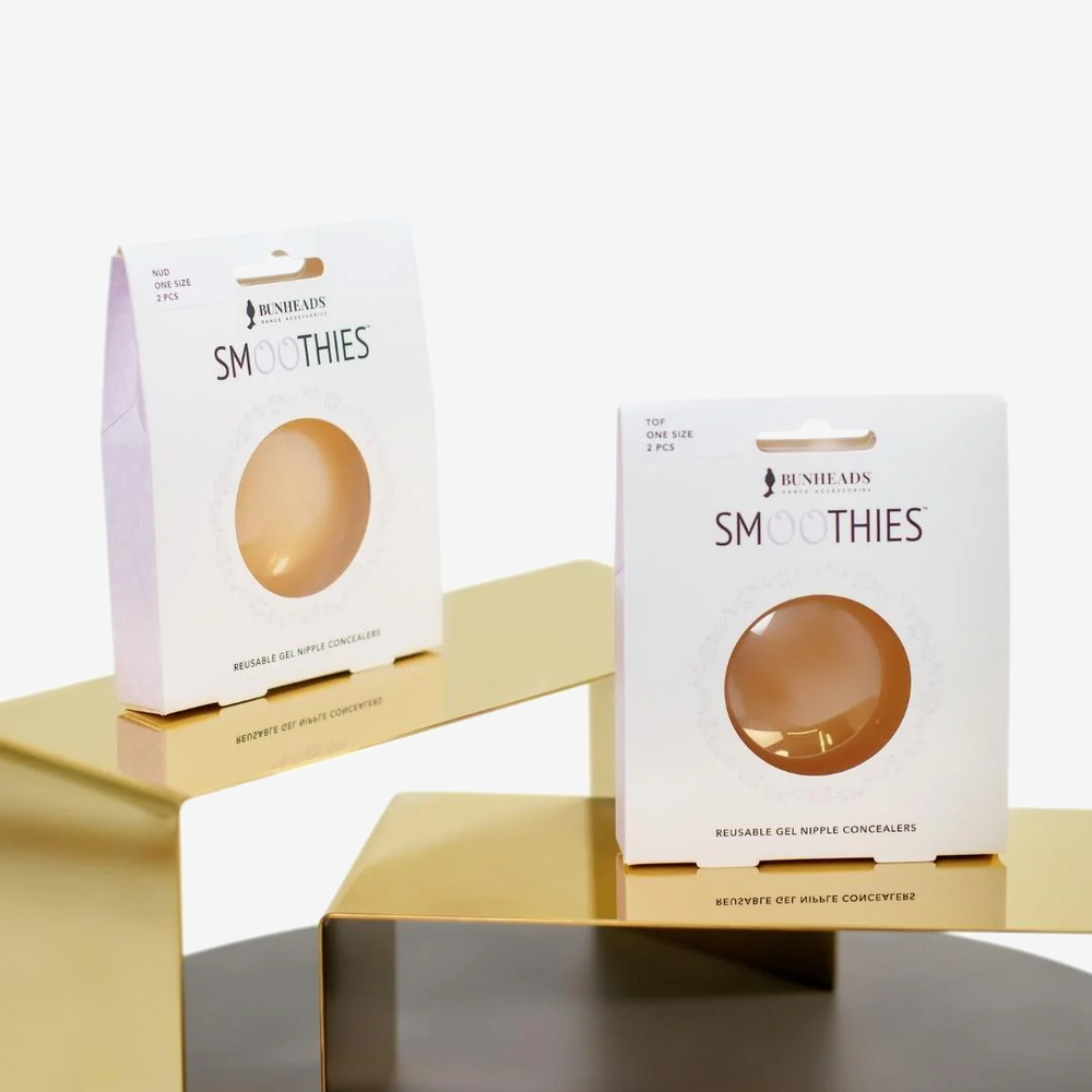 
                      
                        Two boxes of smoothies sit on separate gold stands, staggered, one higher than the other. The back box contains a nude set of smoothies, the front box a toffee set.
                      
                    