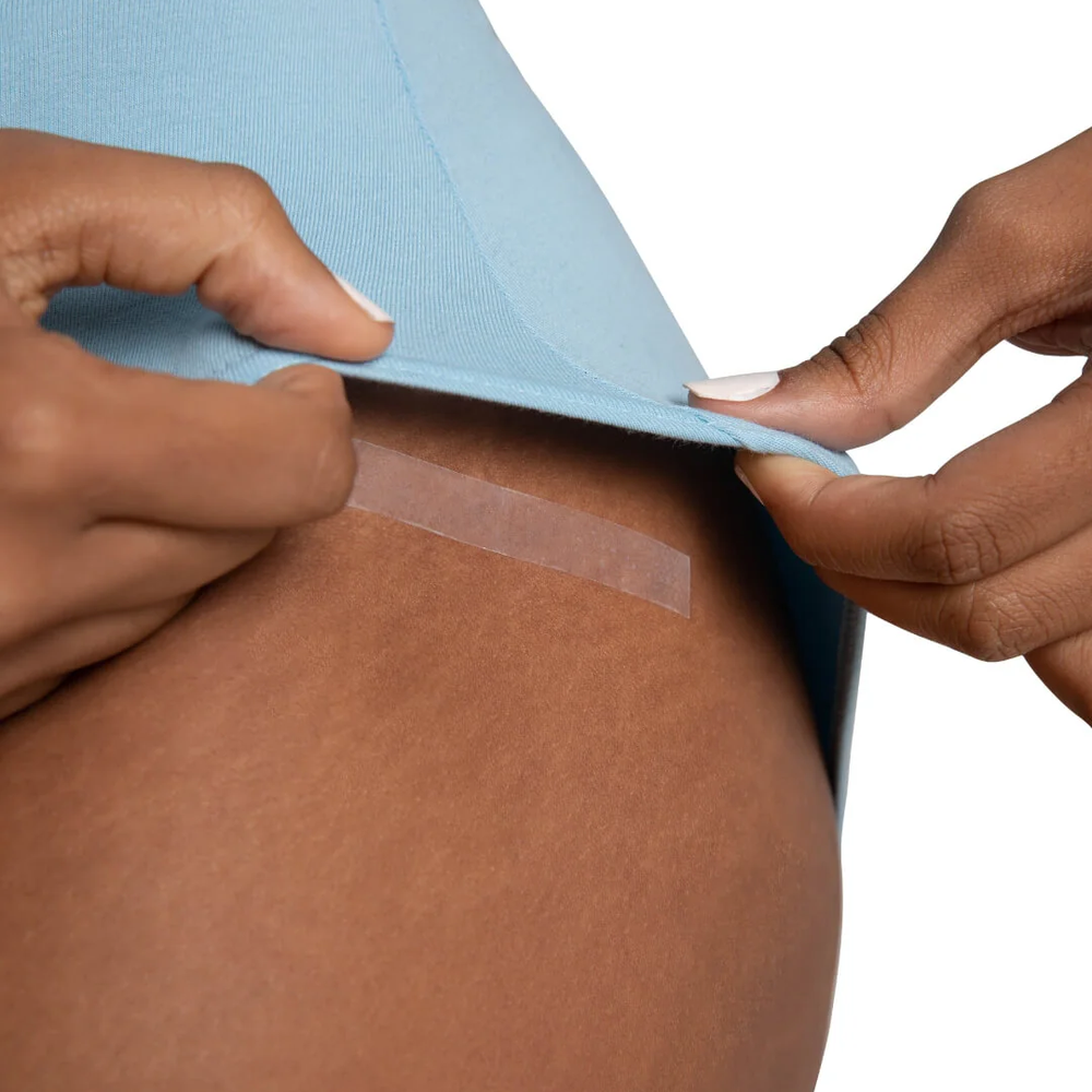 
                      
                        Person applying sticky strip to their skin underneath a blue leotard
                      
                    
