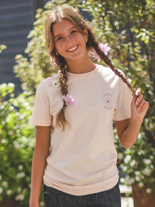 Young girl with braided hair and flowers in her hair, wearing a light-colored t-shirt.