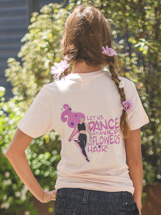 Girl with flowers in her braided hair, wearing a t-shirt with a graphic design and text, outdoors